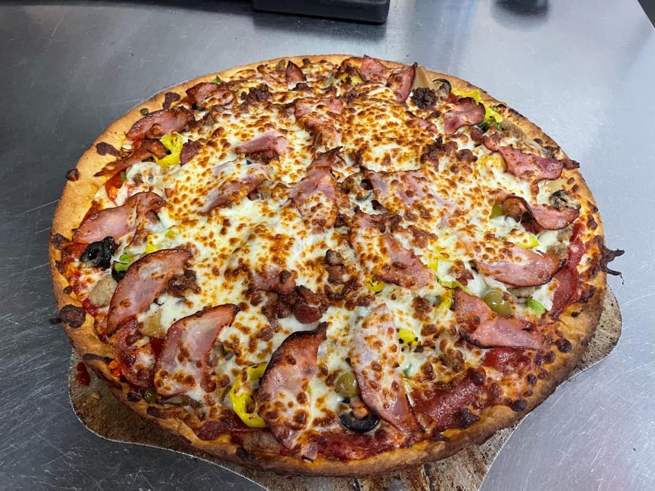 A loaded pizza with ham and bacon